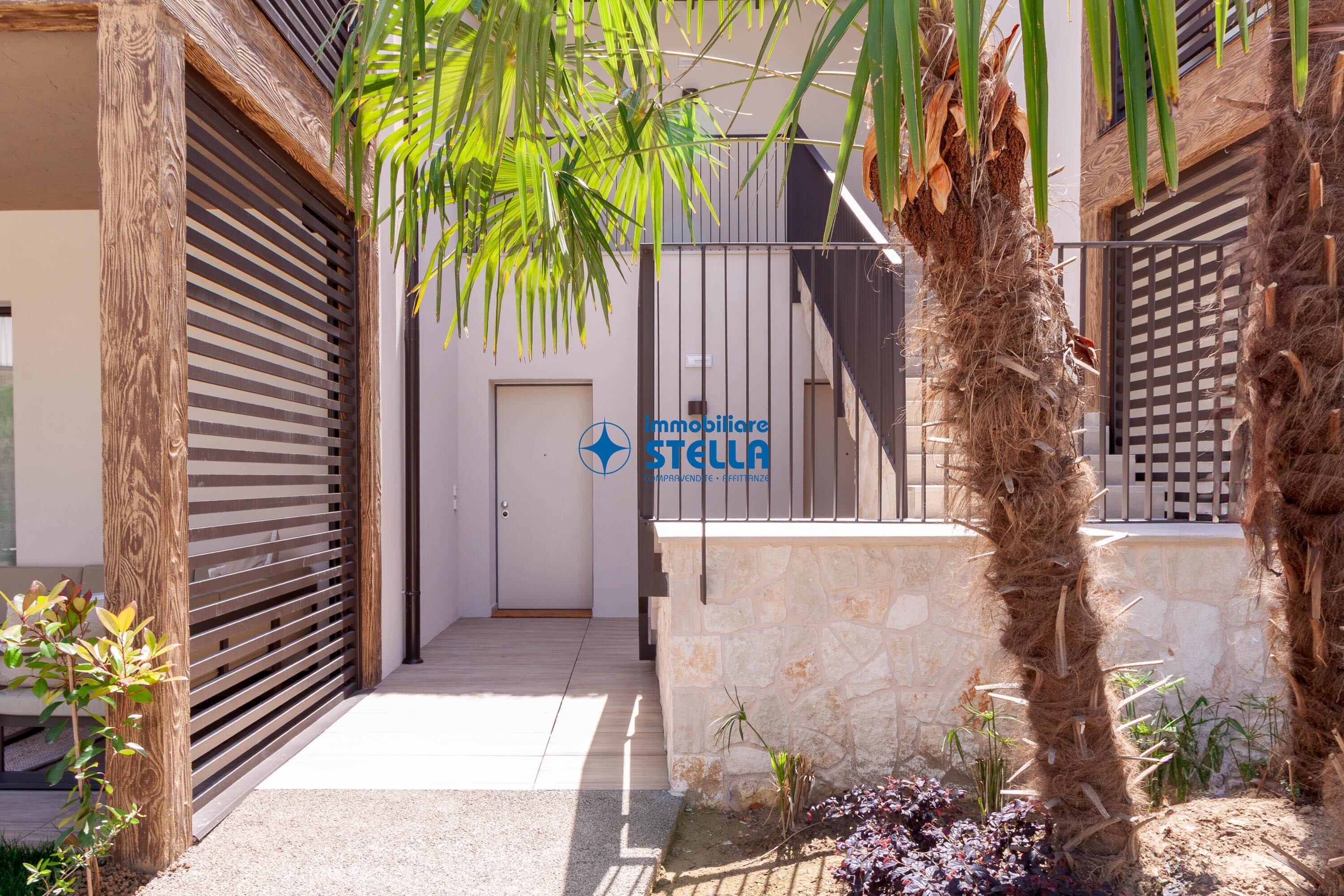 Un edificio moderno con fachada de piedra, puerta de madera y un letrero que dice 'Immobiliare Stella'.