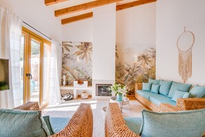 Ein Wohnzimmer mit einer Couch, einem Fernseher, einem Kamin und tropischem Wandpapier.