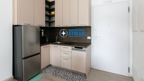 Eine moderne Küche mit Edelstahlgeräten, beigefarbenen Schränken und dem Logo von 'immobiliare STELLA'.