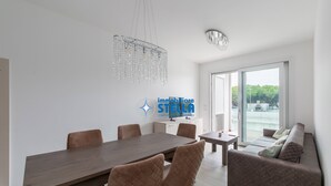 Ein modernes Interieur mit Esstisch, Stühlen, einer Couch, einer Kronleuchter und einem Logo an der Wand.