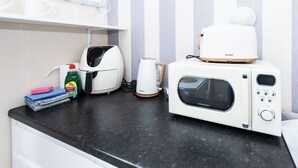 Una encimera de cocina con microondas, tostadora, hervidor y productos de limpieza.