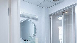 Un baño moderno con cabina de ducha de vidrio, un lavamanos blanco y un espejo con marco decorativo.
