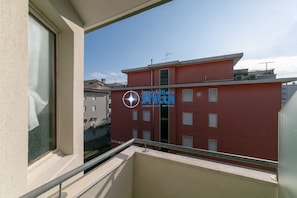 A red building with multiple windows and balconies, viewed from a balcony with a metal railing. - Romeo apt. 22 \ Beach place included \ (Lido di Jesolo)