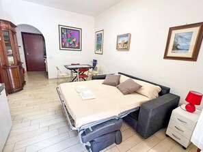 Ein kleines Zimmer mit Bett, Nachttisch und Schreibtisch mit Stühlen.