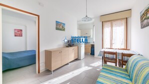 Ett kompakt bostadsutrymme med ett litet kök, en matplats och en soffa.