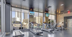 A gym with treadmills, elliptical machines, and a pool view. - High-Floor Studio w/ Stunning Marina Views (Hallandale Beach)