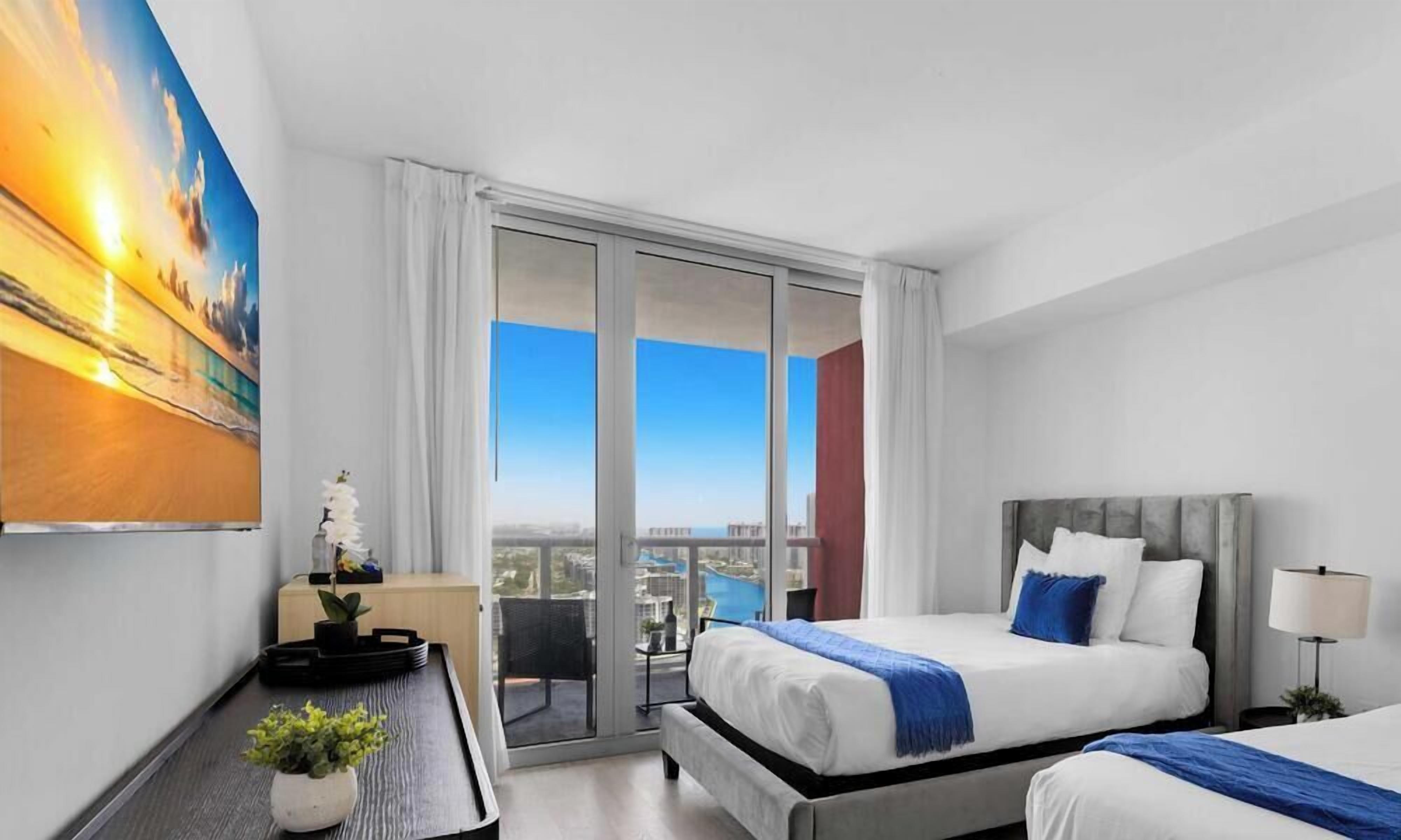 Habitación de hotel con balcón, cama, escritorio y un cuadro.
