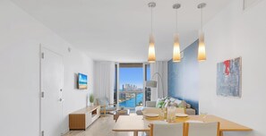 A modern living room with a dining area, large windows with a city view, and a minimalist decor. - Intracoastal View Apt - Beach Shuttle & Full Kitchen (Hallandale Beach)