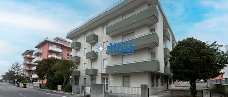 A multi-story building with balconies, a sign for 'immobiliare STELLA,' and a clear sky.