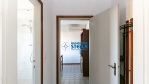 A hallway with a tiled floor, a wooden door frame, and a visible shower area. - Romeo # three-room apartment 19# with beach space° (Lido di Jesolo)