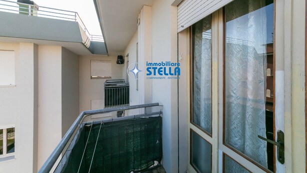A narrow corridor with a metal staircase, a window with frosted glass, and a door with a handle. - Romeo # three-room apartment 19# with beach space° (Lido di Jesolo)