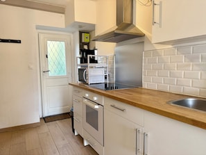 Une cuisine compacte équipée d’un four à micro-ondes, d’une cuisinière et d’un four encastré.