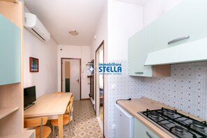 Eine kompakte Küche mit Gasherd, kleinem Kühlschrank und Essecke mit Stühlen und Tisch.