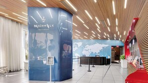 Un área de recepción moderna con un mostrador azul identificado como 'Beachwalk' y un mapa mundial en la pared.