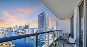 Un balcon offrant une vue sur les toits d’une ville et sur une rivière.