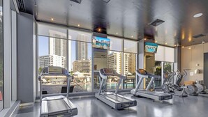 Un gimnasio con cintas de correr, bicicletas estáticas y pesas.