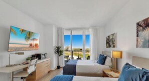 Habitación de hotel con cama, escritorio y un amplio ventanal con vistas a la ciudad.