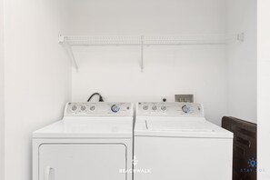 A laundry room with two white washing machines and a metal drying rack. - Airy 2BR · Marina & Bay · Beachwalk Resort (Hallandale Beach)