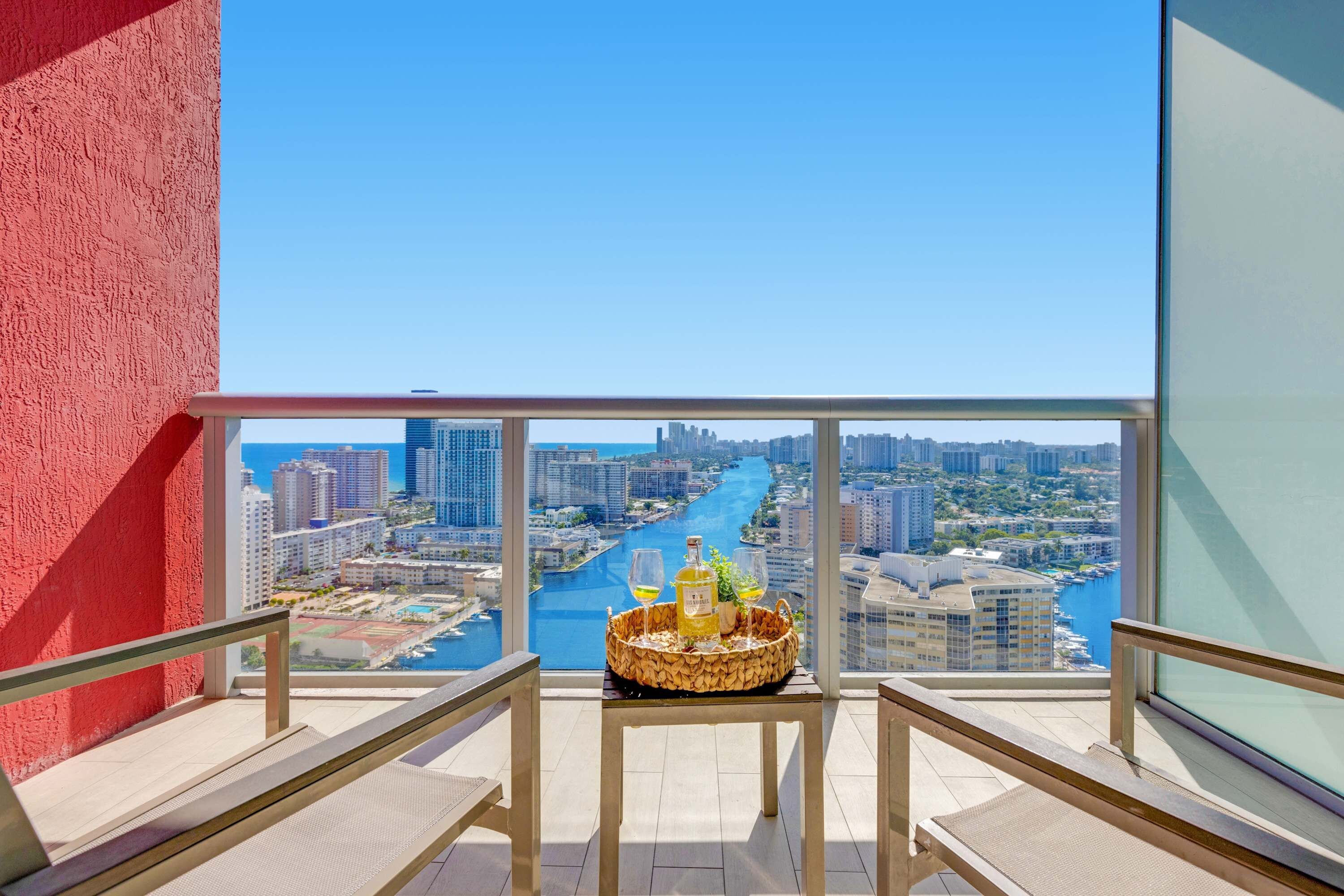 A balcony with a city view, a table with a basket of snacks, and a bottle of liquor.