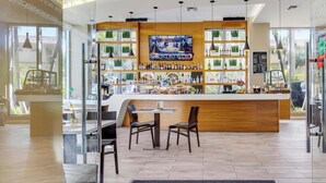 Un área de bar moderna con mostrador de madera, asientos y una pantalla de televisión.