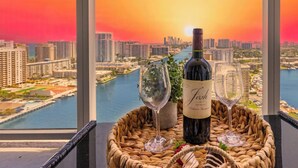A balcony with a view of a cityscape and a body of water at sunset. - Sweeping Sunset Views -2BR Beachwalk Resort (Hallandale Beach)