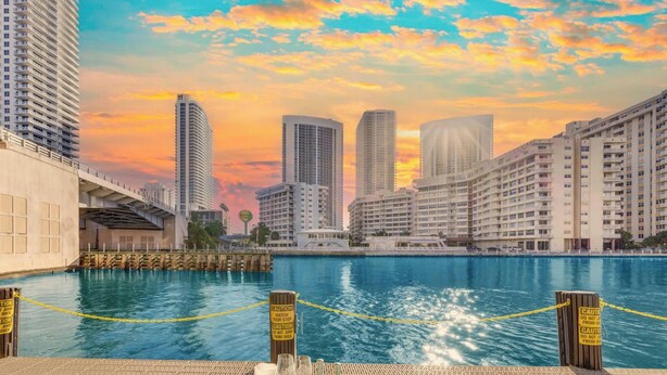 A waterfront dining area with a view of the city skyline, a dock, and caution signs. - Sweeping Sunset Views -2BR Beachwalk Resort (Hallandale Beach)