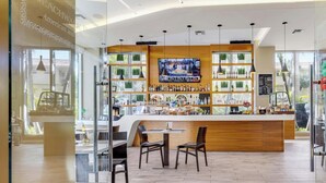 A bar area with a wooden counter, seating, and a TV screen. - Sweeping Sunset Views -2BR Beachwalk Resort (Hallandale Beach)