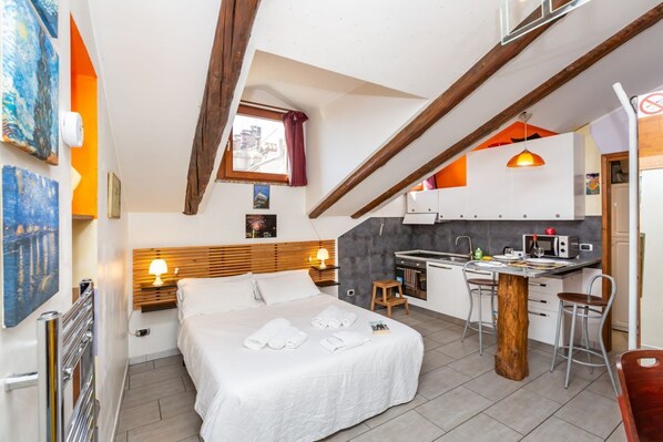 Ein kompaktes Hotelzimmer mit Bett, einer kleinen Küchenzeile, einem Essbereich und einem Fenster mit Blick.