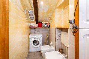 A compact bathroom with a washing machine, a toilet, and a shower area. - GuestHost - La Mansarda di Garibaldi (Turin)