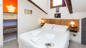 Un dormitorio con cama, lámparas de noche, una ventana y una repisa con un jarrón.