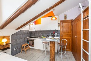 A compact kitchen with a wooden ceiling, a small dining area, and a wooden cabinet. - GuestHost - La Mansarda di Garibaldi (Turin)