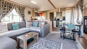 A compact living space with a sofa, a dining table, and a kitchenette. - St Andrews Holiday Park | Harbour Reach (No 11) (St Andrews)