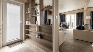 A modern living room with a sofa, a coffee table, and a staircase with built-in shelves. - Lodge No 138 | Stewarts Resort Cameron (Cameron)