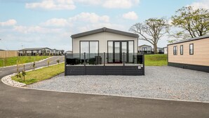 A modern building with a flat roof, large windows, and a gravel driveway. - Lodge No 138 | Stewarts Resort Cameron (Cameron)