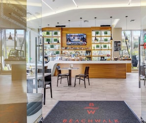 A modern bar area with a TV screen, wooden counter, and seating. - Modern Studio | Sunset Views | Beachwalk Resort (Hallandale Beach)