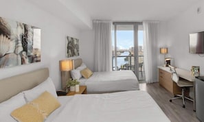 A hotel room with a bed, desk, TV, and a view of a cityscape. - Modern Studio | Sunset Views | Beachwalk Resort (Hallandale Beach)