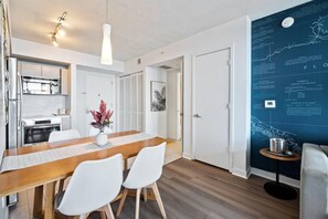 Une cuisine moderne avec des armoires blanches, un réfrigérateur en acier inoxydable et un four encastré.