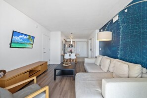 Un salon moderne comprenant un canapé, une table basse, un téléviseur et un coin repas avec des chaises et une table.