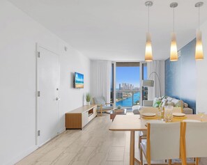 A modern living room with a dining area, large windows with a city view, and a minimalist decor. - Bright Apt, Intracoastal View | Balcony & Pool (Hallandale Beach)