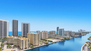 A coastal cityscape with high-rise buildings, a marina, and a clear blue sky. - Intracoastal View Apt | Private Balcony & Full Kitchen (Hallandale Beach)