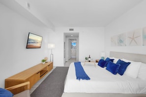 A modern hotel room with a bed, bedside table, lamp, and artwork on the walls. - Intracoastal View Apt | Private Balcony & Full Kitchen (Hallandale Beach)