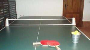 Een tafeltennistafel met twee rode batjes en een emmer gele ballen.