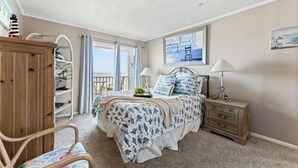 Ein Schlafzimmer mit Bett, Holzschrank, Stuhl, Nachttisch und Balkonblick.
