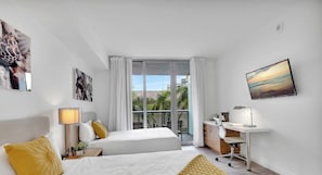 A modern hotel room with a bed, desk, and large window. - Sunset Views  2BR -2BTH (Hallandale Beach)