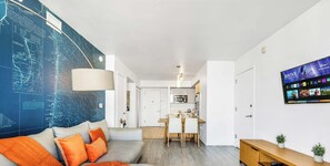 A modern living room with a sofa, a dining area, and a kitchen in the background. - Top-Floor 1BR · Bay View · Beachwalk Resort & Gym (Hallandale Beach)