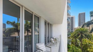 Ein Balkon mit Blick auf Palmen und hohe Gebäude.