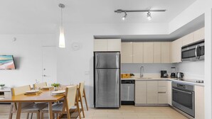 Une cuisine moderne dotée d’appareils électroménagers en acier inoxydable, un coin repas avec des meubles en bois et un design minimaliste.