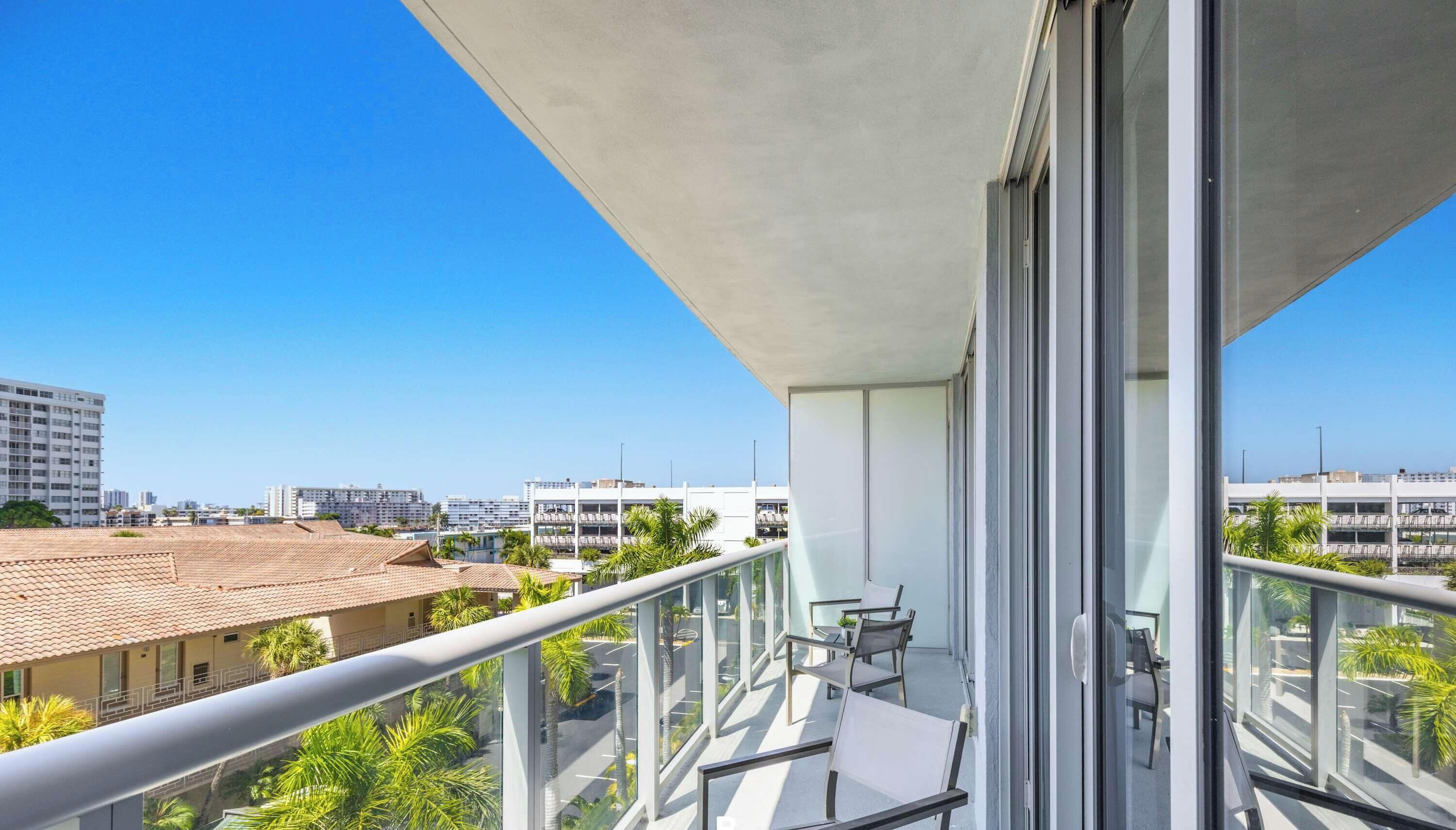 Un balcon offrant une vue dégagée sur le paysage urbain, avec les bâtiments et les palmiers en évidence.