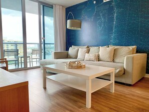 Een moderne woonkamer met een bank, een salontafel en een wand met kaarten.