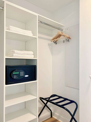 Ein weißer Kleiderschrank mit Regalen, einer Kleiderstange und einem digitalen Schloss.